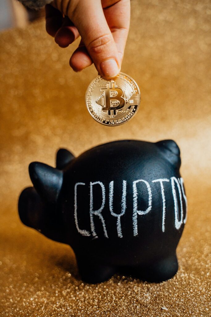 Hand gold bitcoin coin going into black piggybank