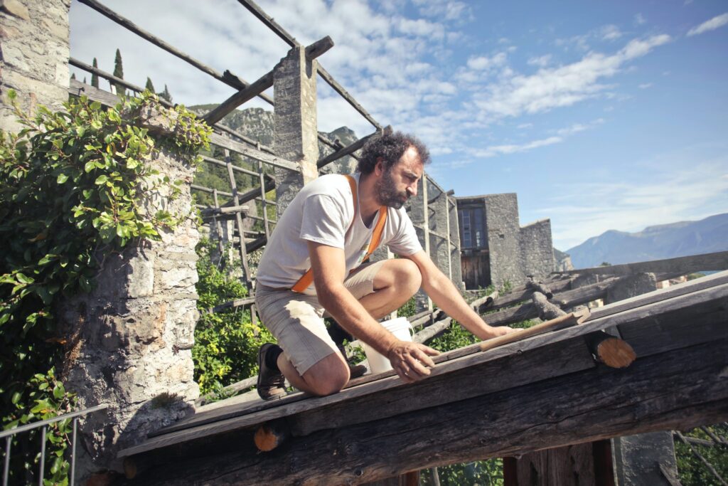 Man scaling and constructing wooden roof