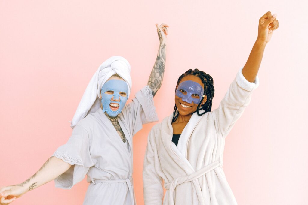 Photo of two women celebrating in bathrobes and face mask treatments