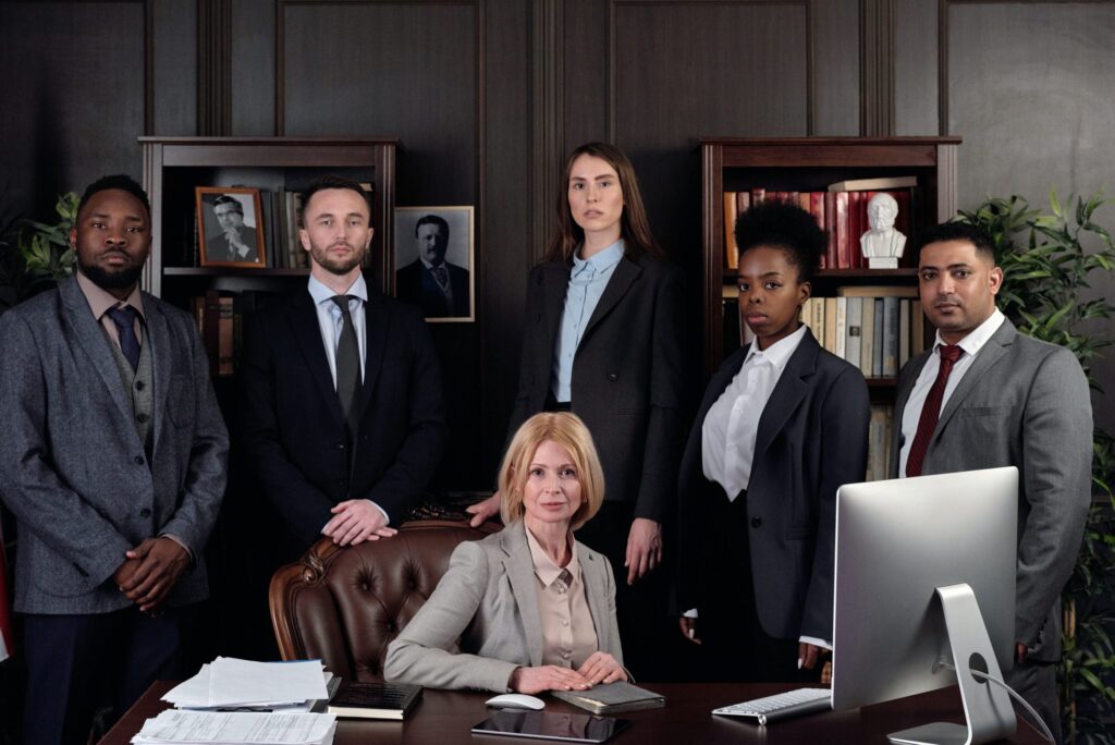 Team of professionals standing behind business woman sitting at a desk