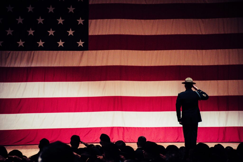 Soldier saluting large backdrop of American flag