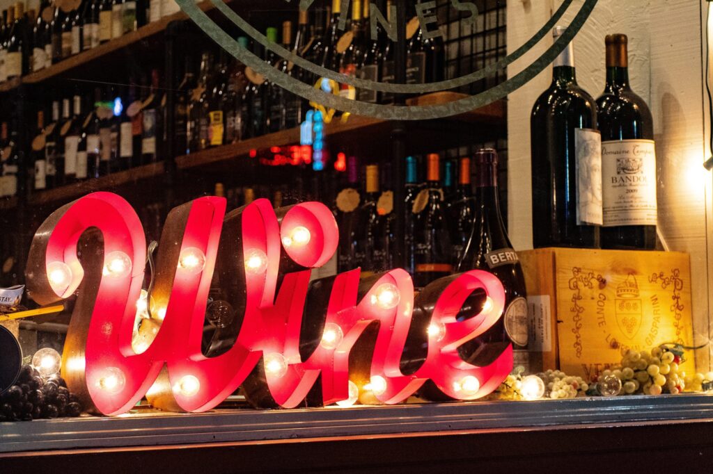 Red 'wine' marquee sign on bar with assortment of liquor bottles behind it