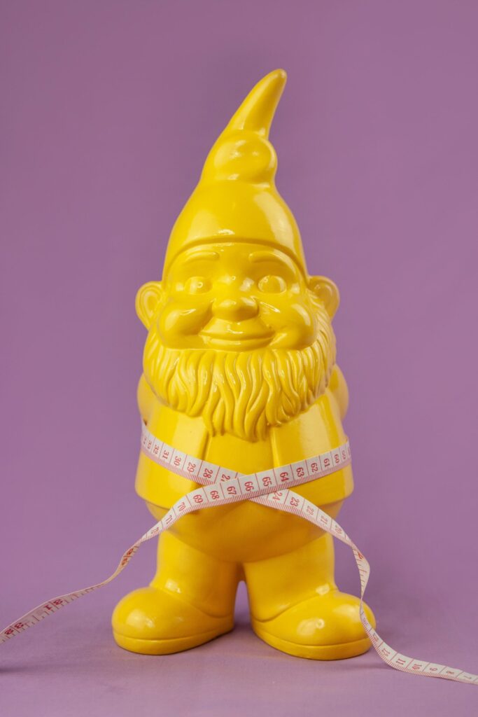 Yellow garden gnome with white measuring tape around its waist