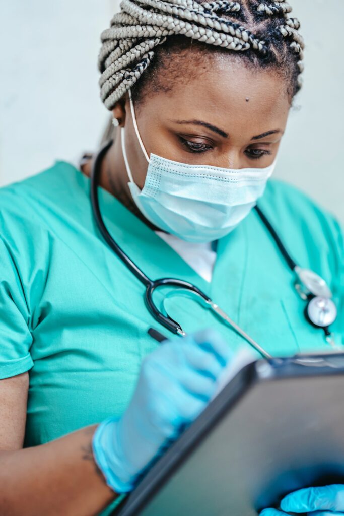 Nurse wearing surgical mask and writing on clipboard