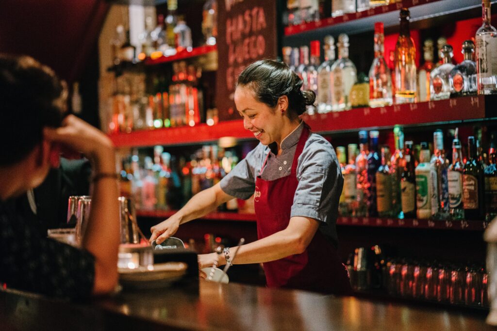 Woman bartender smiling while mixing drinks