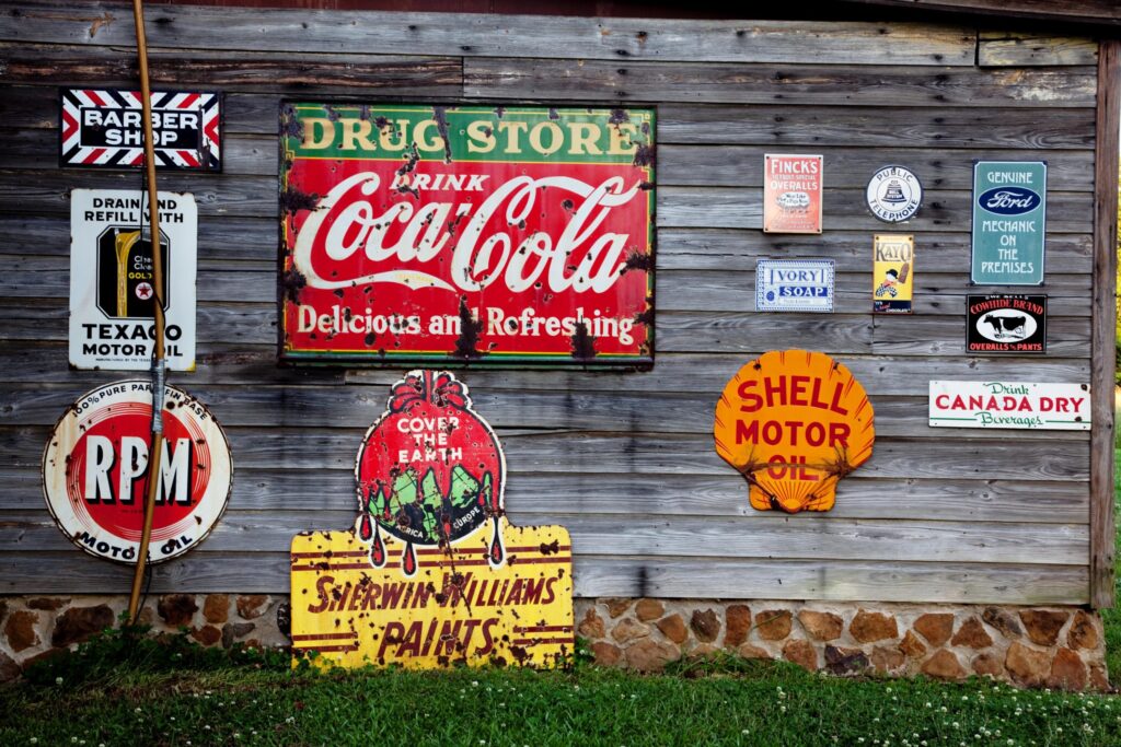 Wooden wall featuring various signs of logos such as coca cola and shell motor