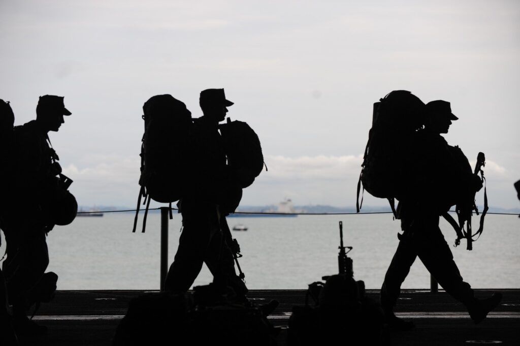 Silhouette of three soldiers walking in line with equipment