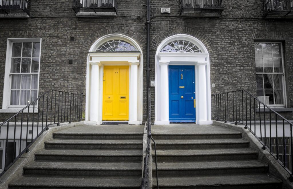 Blue and yellow doors against grey scale brownstones